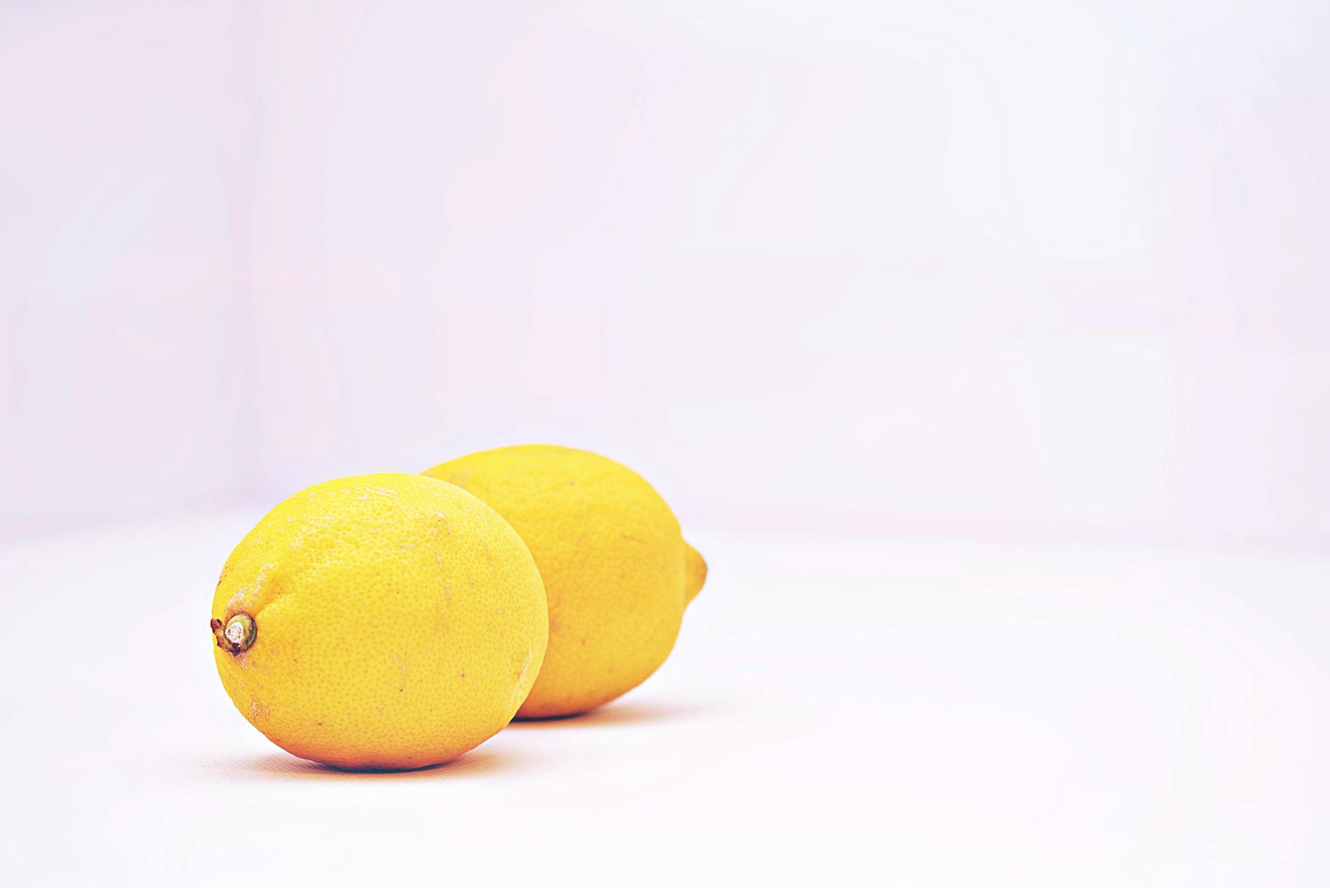 Two vibrant lemons placed against a minimalistic white background, representing the reset of sensation after a break.