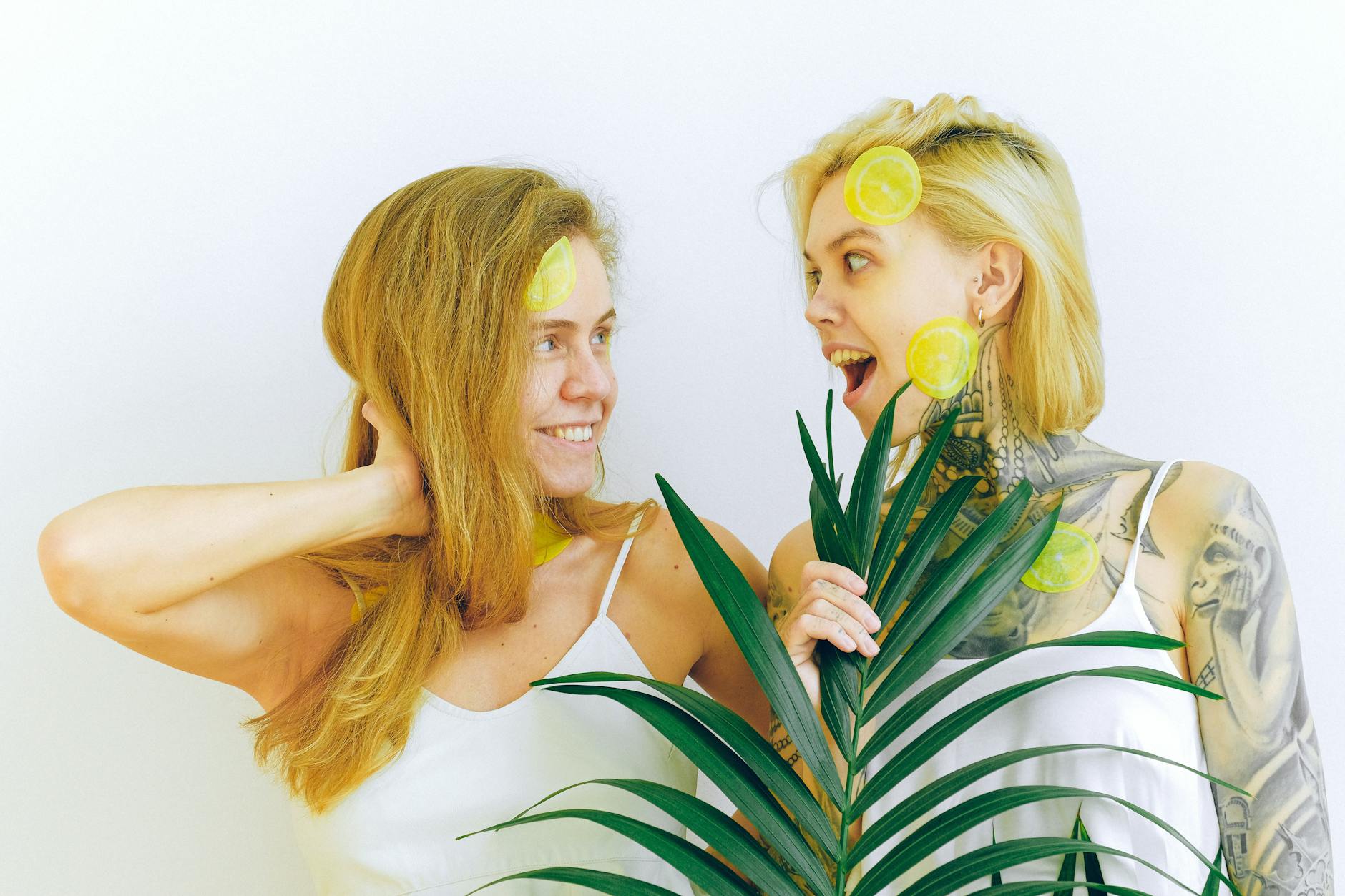 Two women laughing together with lemon slices, expressing confidence and pleasure