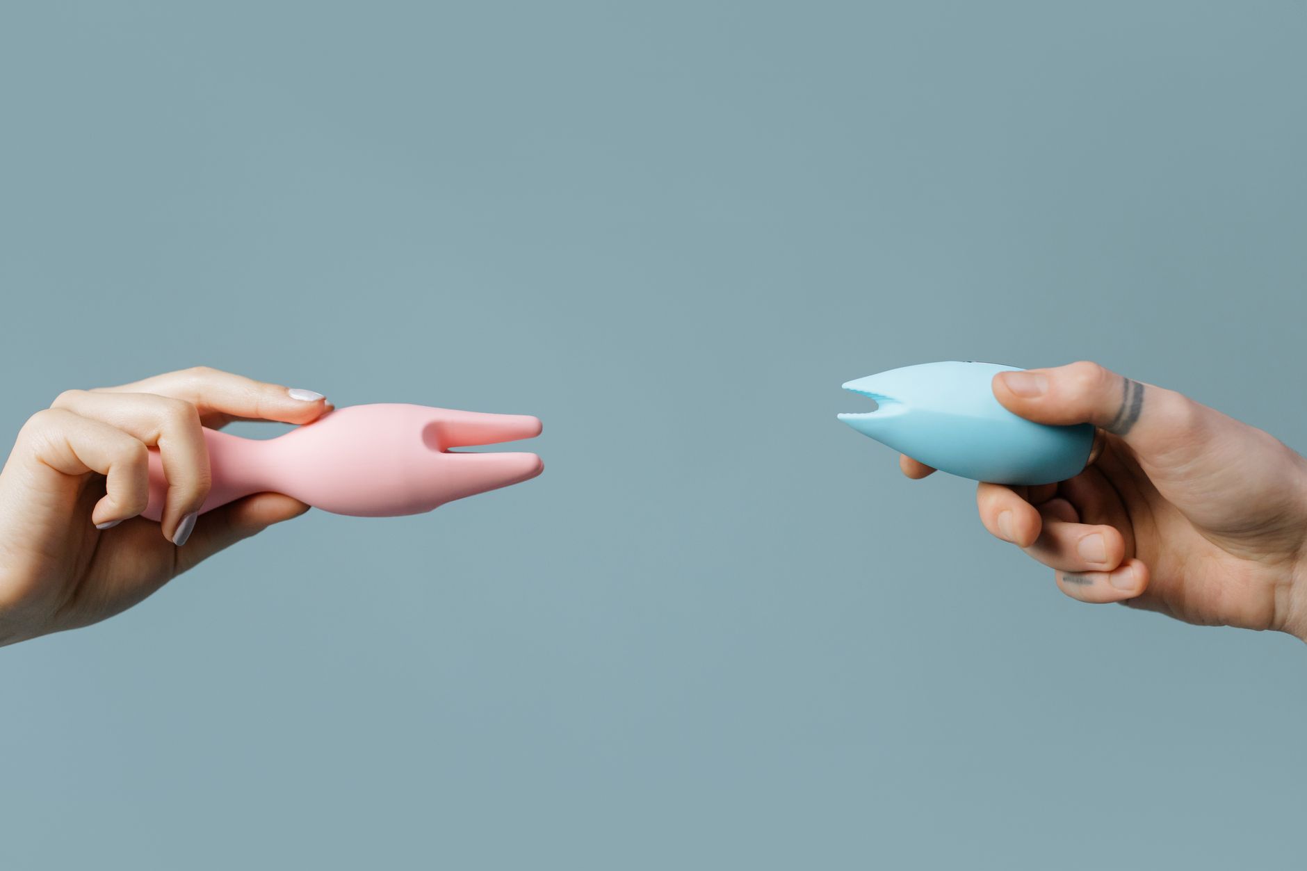 Hand holding a lemon on a soft pink background with additional lemons arranged nearby