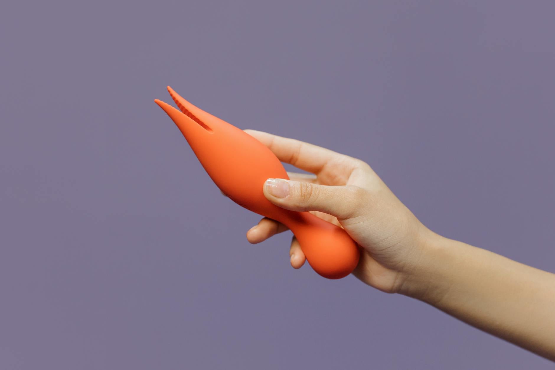 A hand holding a sleek vibrator against a minimalist purple backdrop, showcasing modern sensual design